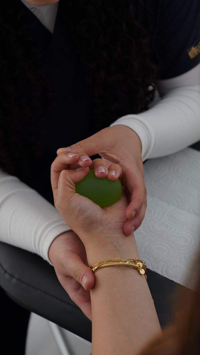 Hands engaged in a physiotherapy session using a stress ball for wrist strength and rehabilitation.
